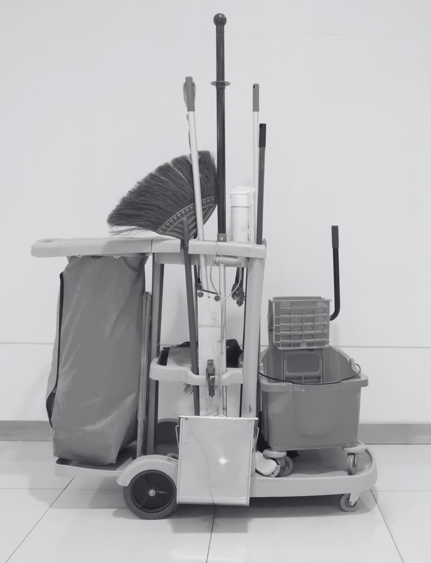 Janitorial cart with mop, broom, bucket and wringer against a wall